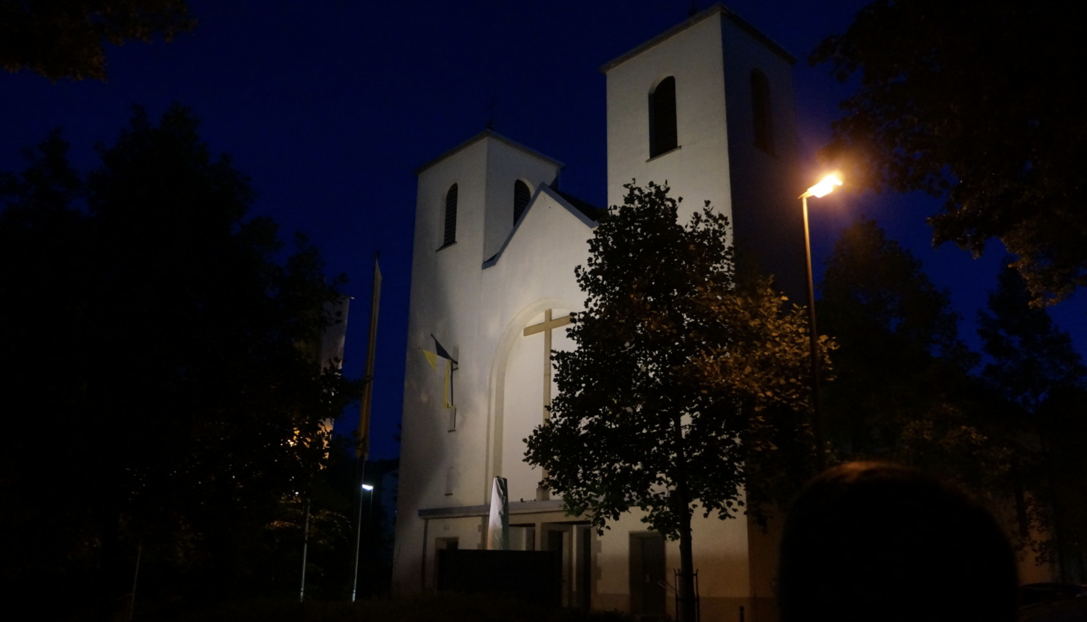 St. Antonius Kirche in der blauen Stunde - Kirche bei Dämmerung mit beleuchtetem Kreuz